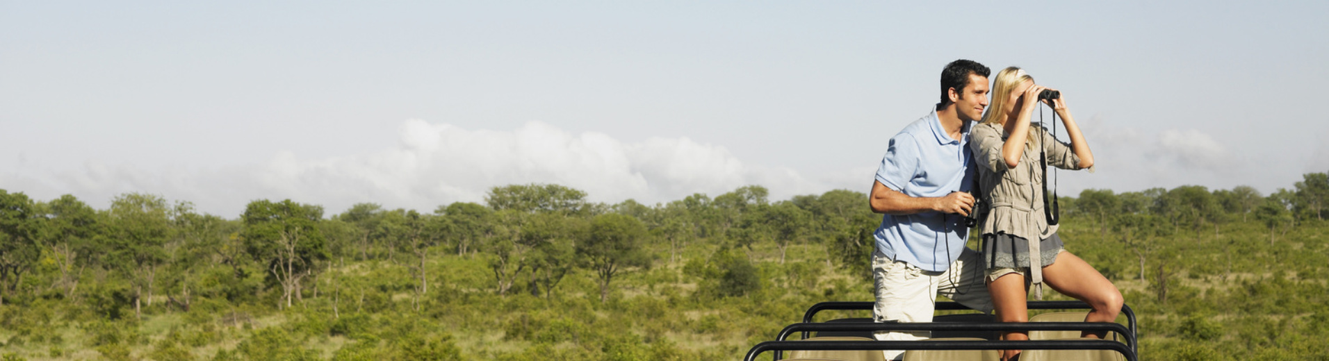 couple dans une Jeep en plein safari dans la savane avec des jumelles